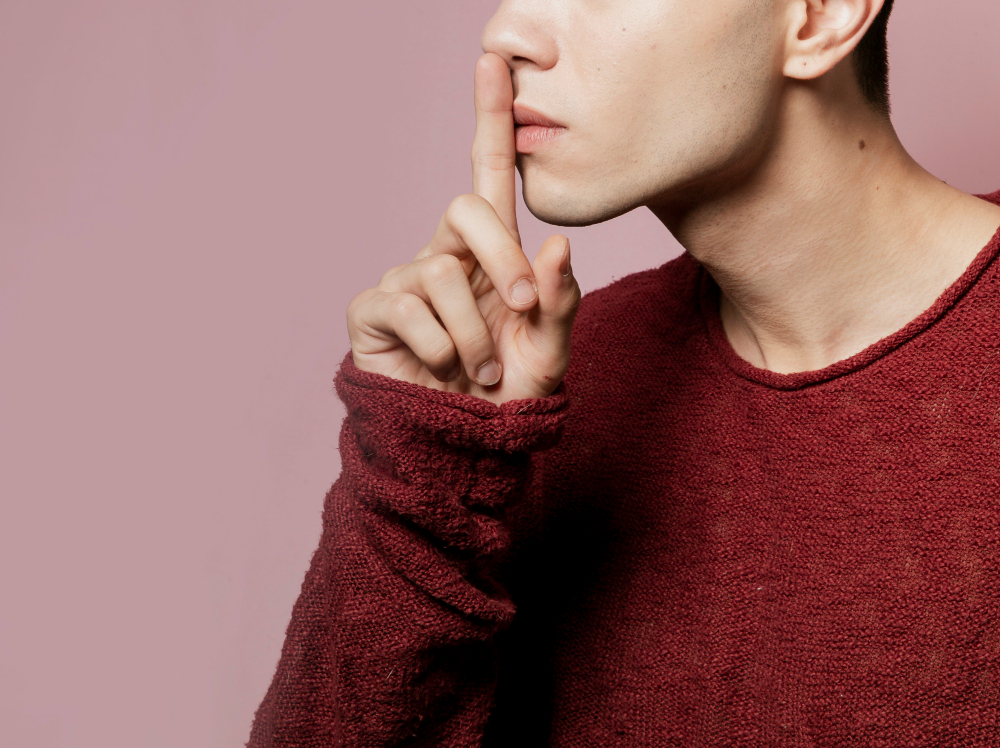 Persona haciendo gesto de silencio con el dedo sobre los labios, concepto del silencio electoral en Ecuador 2025.