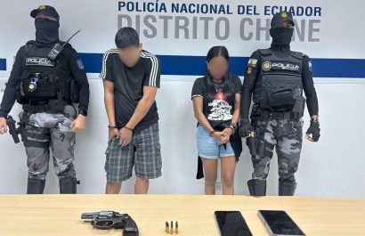 La pareja detenida junto al arma de fuego que se les encontró después de una persecución.